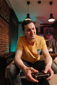 A young man in a yellow shirt intensely playing a video game with a controller.