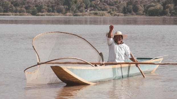 Smiling fisherman in a boat using a net on Lake Janitzio, Michoacán, Mexico.