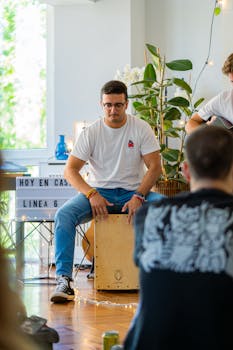 Young adults enjoy a casual indoor jam session with cajon and guitar.